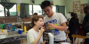 Dos estudiantes en el aula usan un microscopio logrando un aprendizaje por descubrimiento.