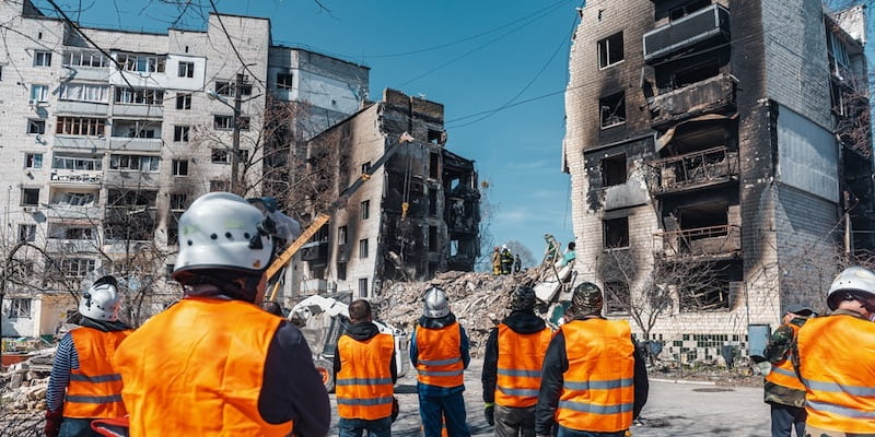 Um grupo de homens observa a crueldade da destruição em uma guerra